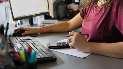 a person calulating figures by a computer
