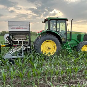 Tractor planting cover crops into corn.