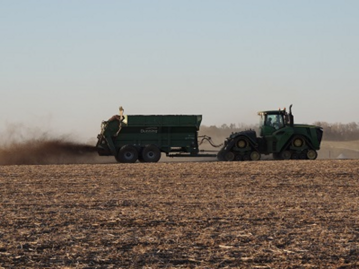 A tractor spreading manure on a field